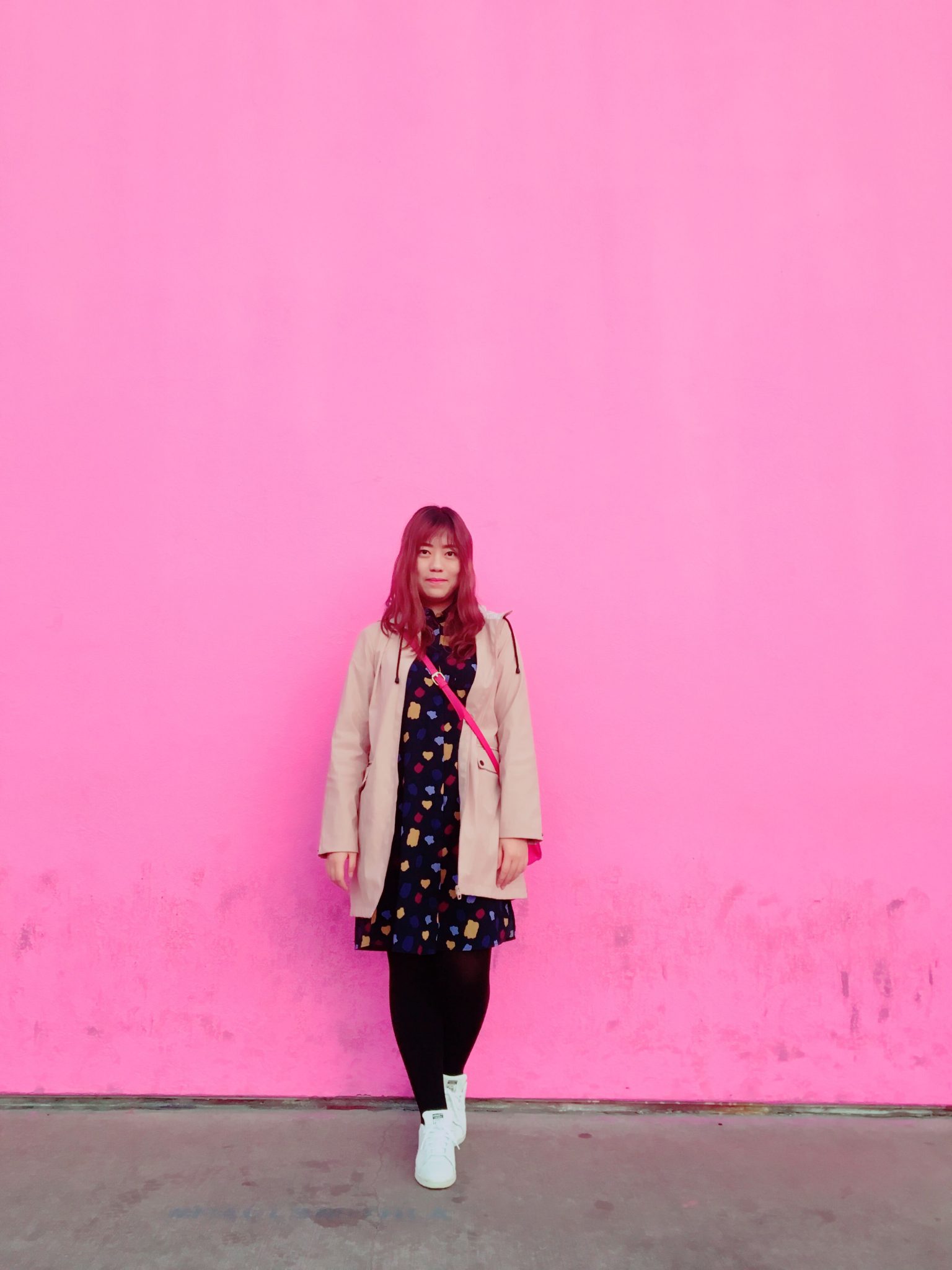 Chinese girl standing up against a pink wall